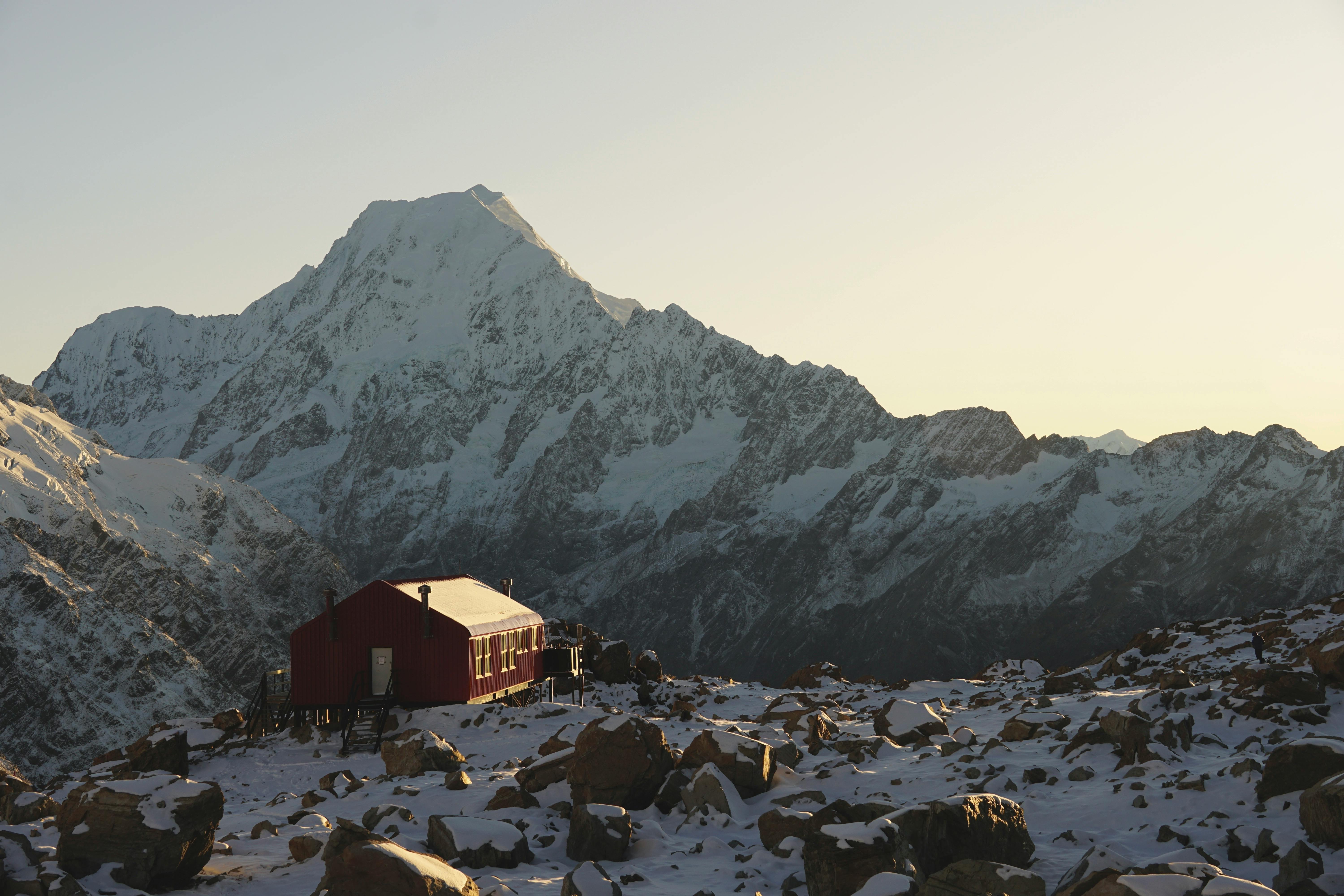 Stunning winter vista of a red hut against snowcapped peaks in Mount Cook National Park.