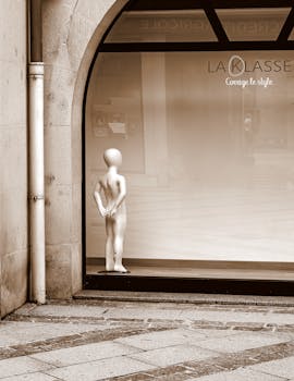 Sepia-toned storefront window with a single child mannequin in a minimal urban setting.
