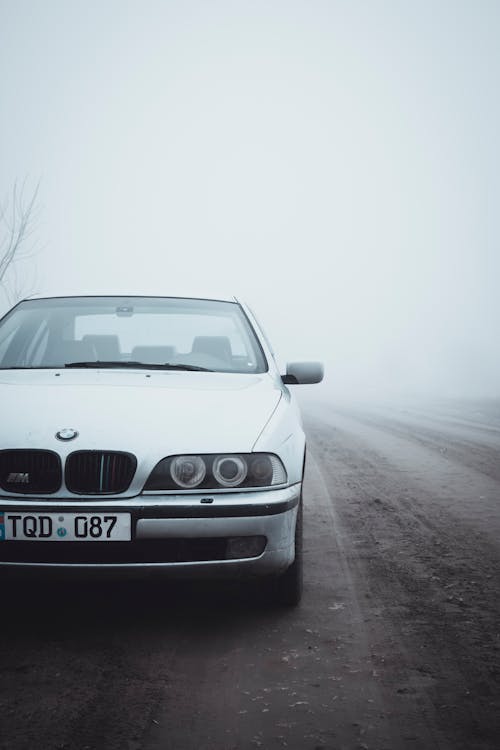 A white car is parked on a foggy road