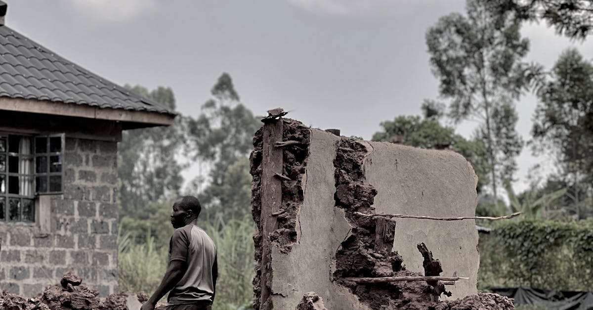 Photo by Eddie* Malika* A man walks through the rubble of destroyed buildings in a rural village setting, highlighting post-destruction life.