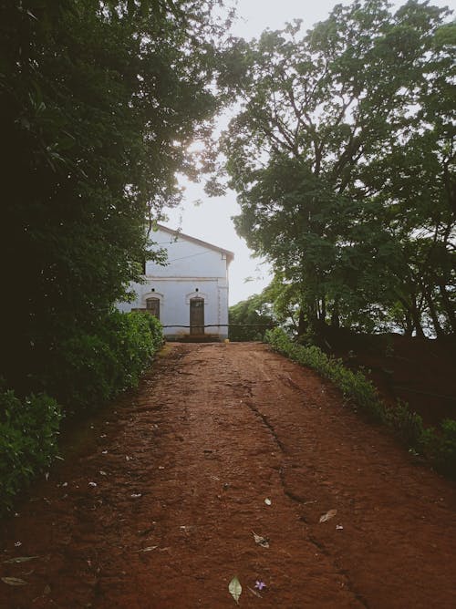 A dirt road leading to a white house