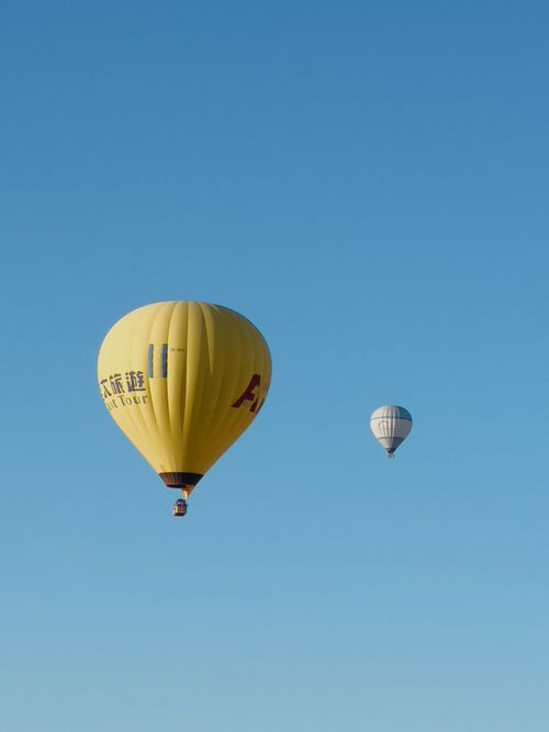 Free Two colorful hot air balloons float peacefully in a clear blue sky, capturing adventure spirit. Stock Photo
