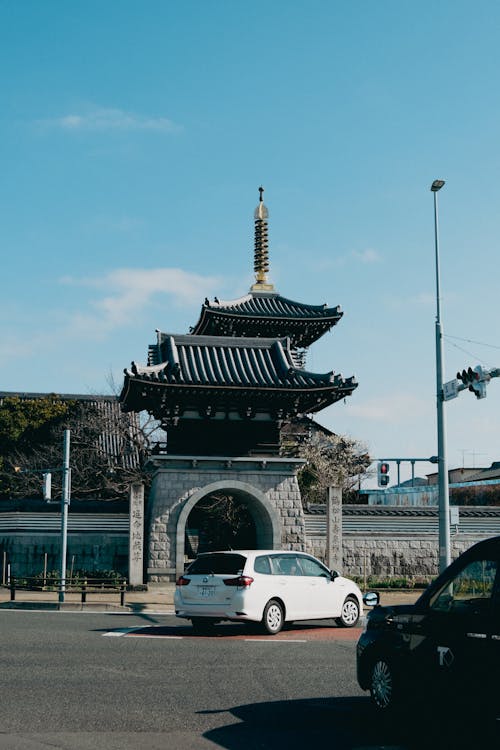 A car driving down the street in front of a pagoda