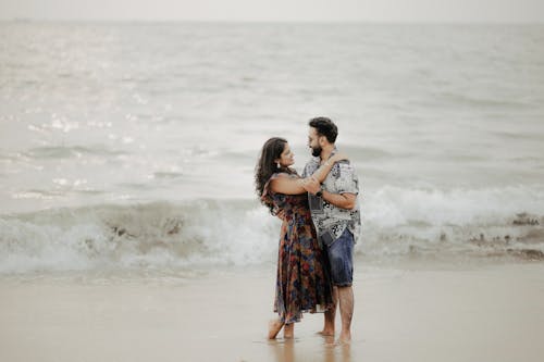 A Couple Hugging while Standing on the Beach 