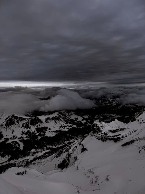 Scenic View of Snowcapped Mountains under Dramatic, Dark Clouds