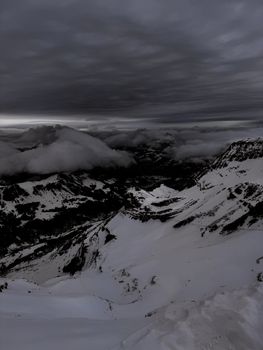 Moody sky and snowcapped peaks in Saanen, Switzerland, showcasing dramatic weather and landscape.