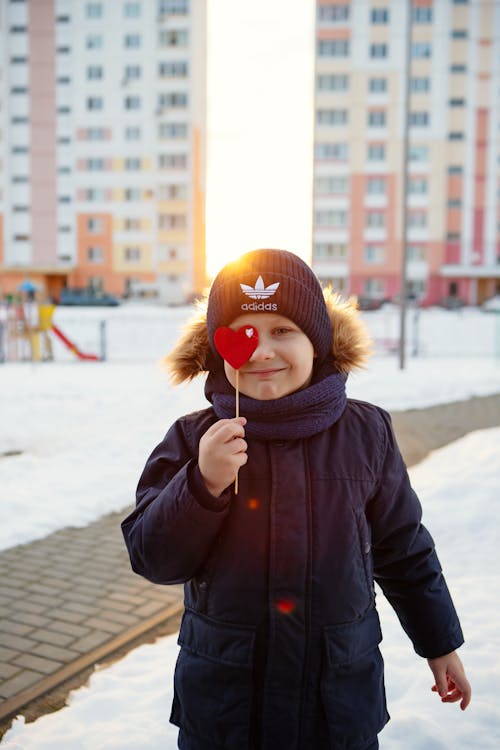 A young boy holding a heart shaped object in the snow