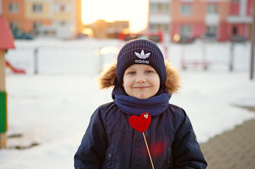 A young boy holding a heart shaped object in the snow