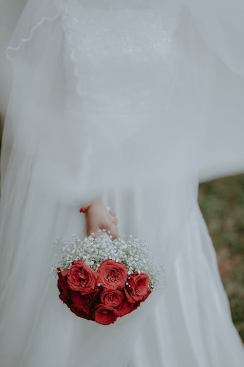A bride holding a red bouquet in her hand