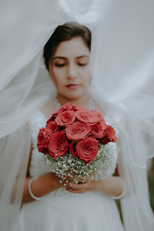 A bride holding a bouquet of red roses