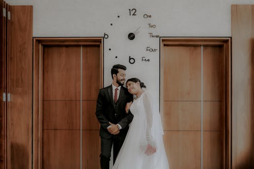 Newlyweds Standing under Clock on Wall