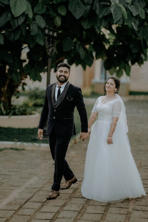 Woman and Man Holding Hands in Wedding Suit and Dress