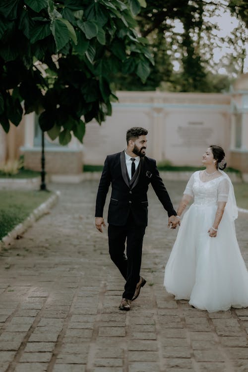 Newlyweds in Suit and Wedding Dress Walking at Park