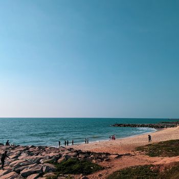 A tranquil beach scene with people enjoying the shoreline under a clear blue sky, perfect for summer travel.