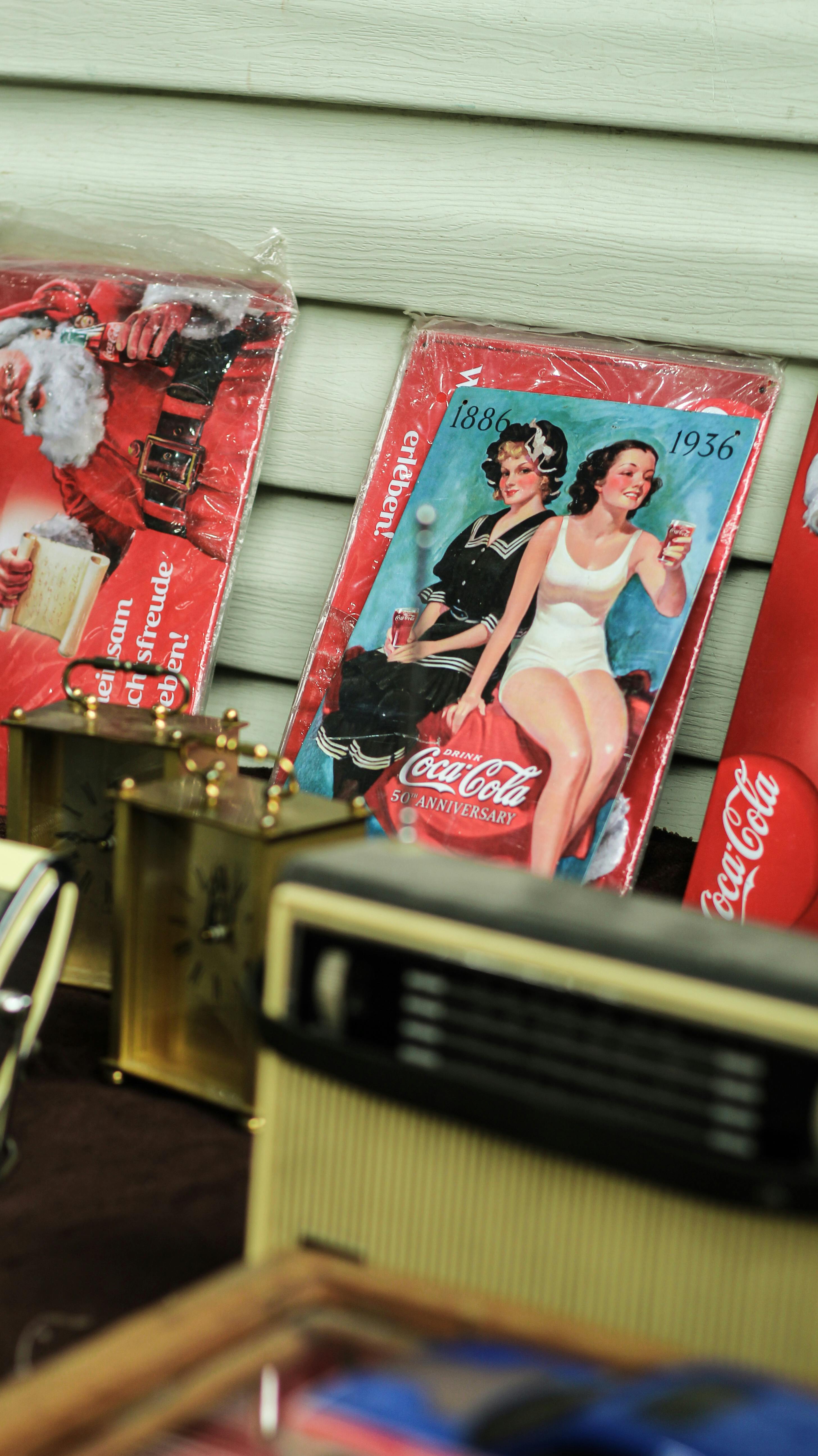 Vintage Coca Cola advertisements with retro clocks and radios on display.