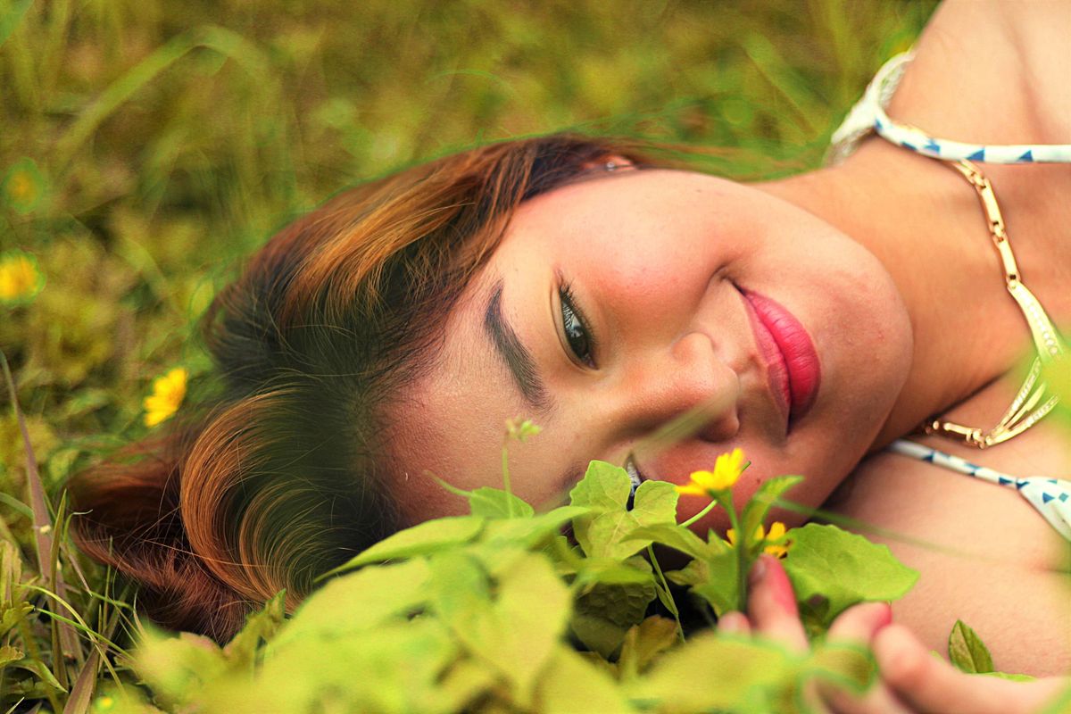 Person looking at a flower while laying in the grass