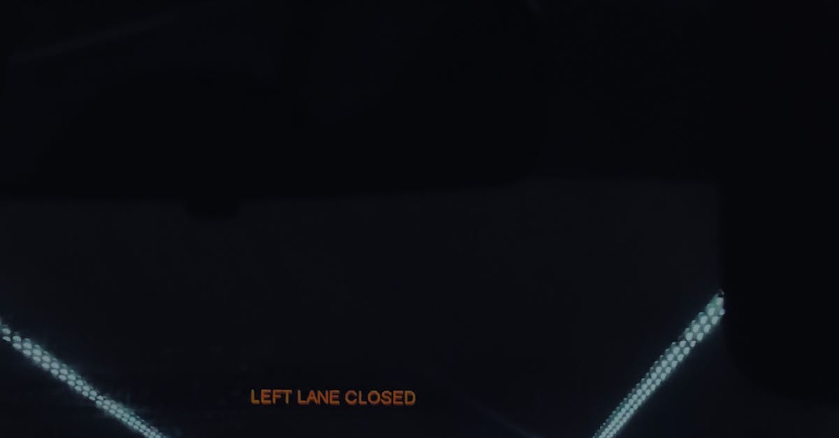 Photo by Beard Kid Dimly lit Dubai tunnel with 'Left Lane Closed' sign and flowing traffic at night.