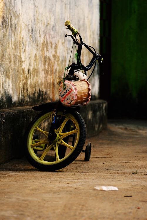 Free A bicycle with a drum leans against a weathered wall in Sundargarh, India. Stock Photo