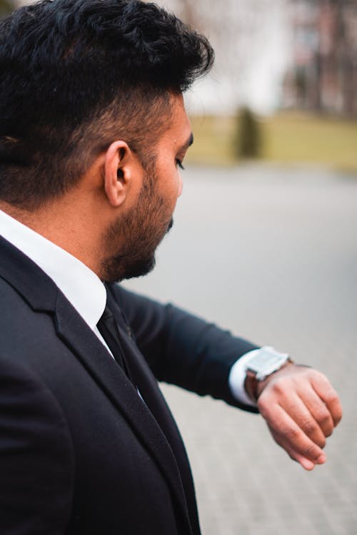 A man in a suit and tie is looking at his watch