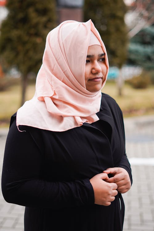A woman in a hijab is standing outside