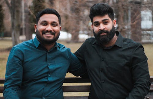 Two men are sitting on a bench in the park