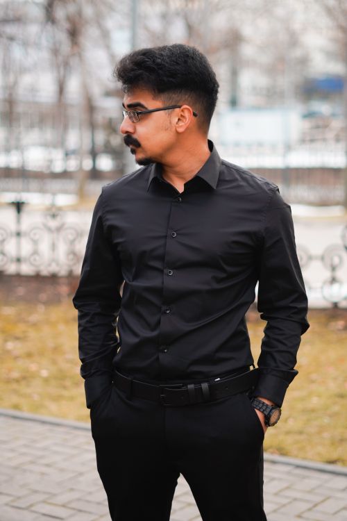 Free Fashionable man in black standing outside, hands in pockets, looking away Stock Photo