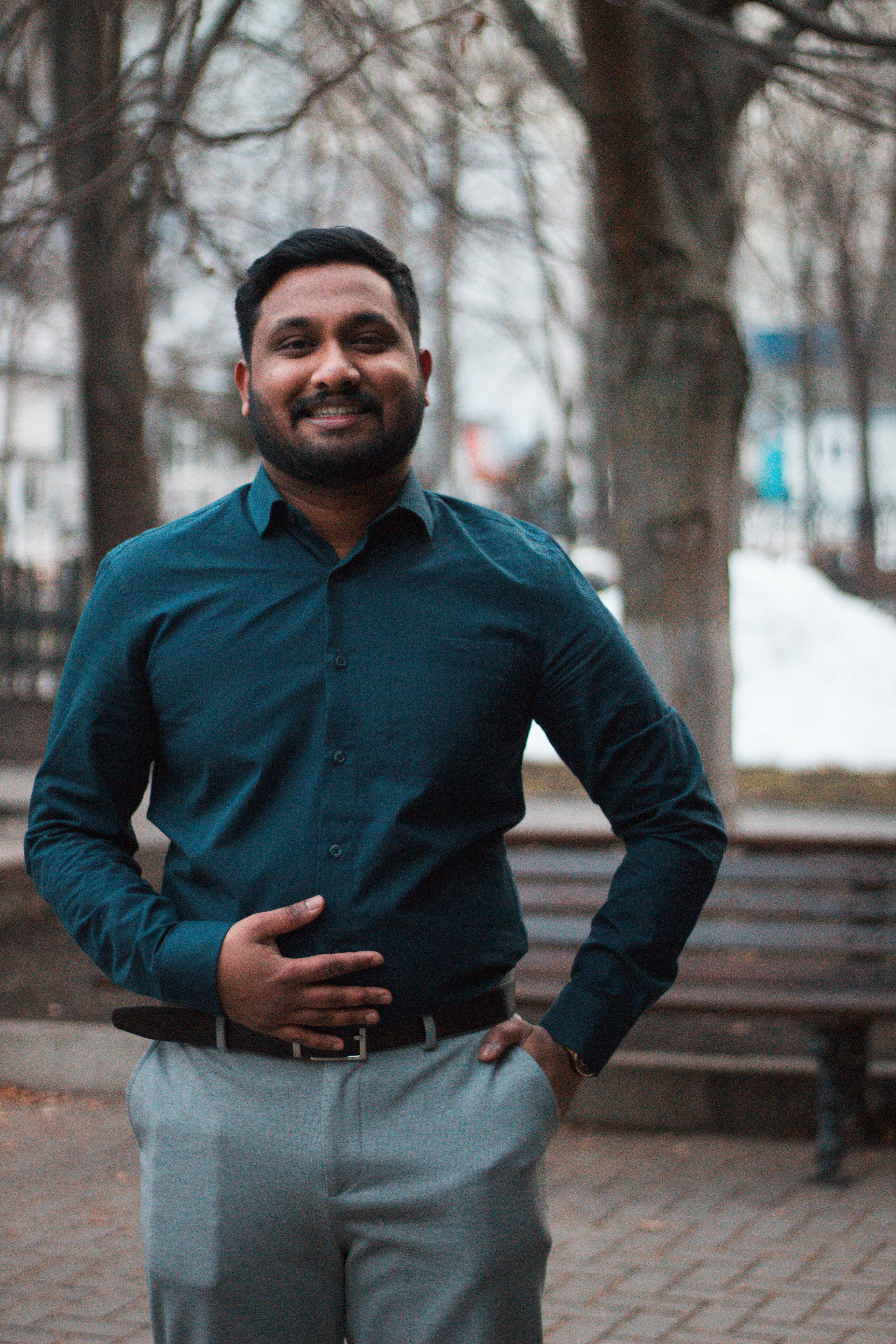 A well-dressed man smiling confidently in an outdoor setting during daytime.