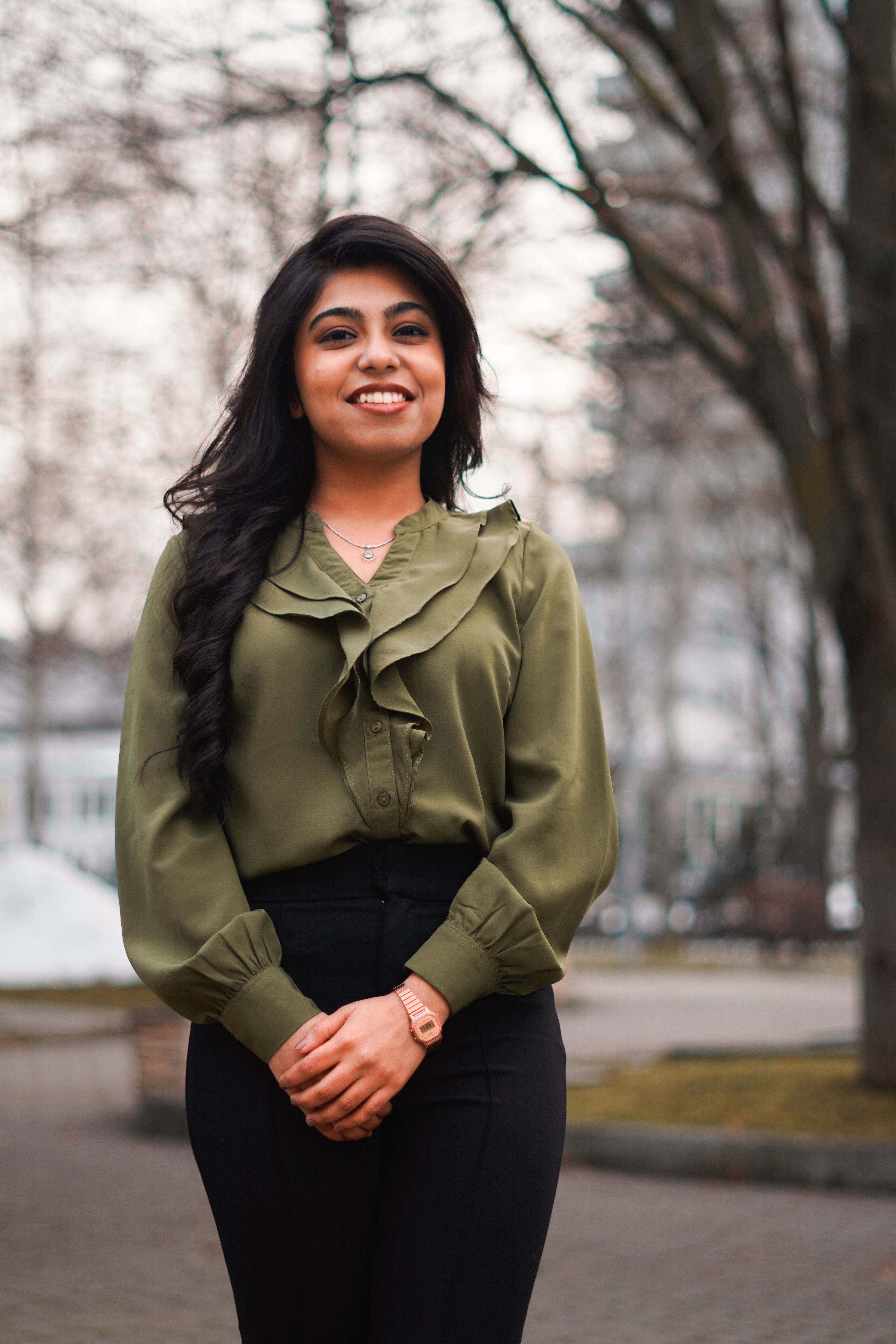 Smiling woman in elegant attire posing outdoors during winter, expressing confidence and warmth.