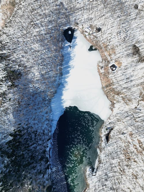 Aerial View of a Half Frozen Lake in a Winter Forest