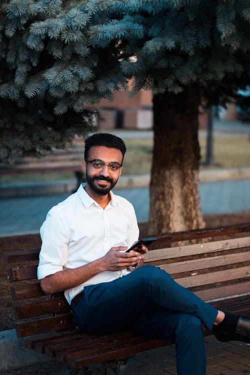 A man sitting on a bench with his phone