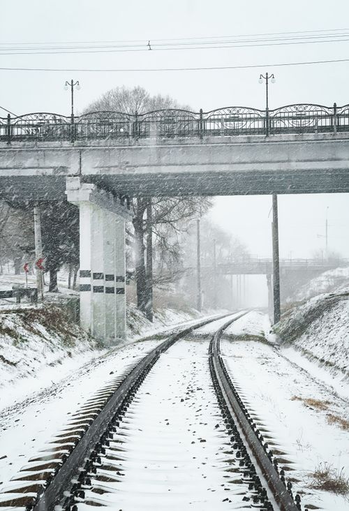 Free Railway tracks beneath a bridge covered in snow on a winter's day. Stock Photo