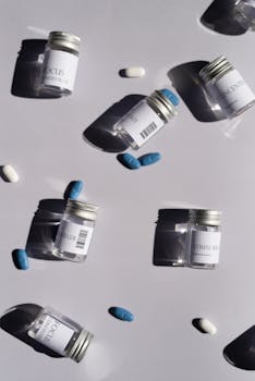 Artistic flat lay of medicine bottles and pills against a white background, casting shadows.