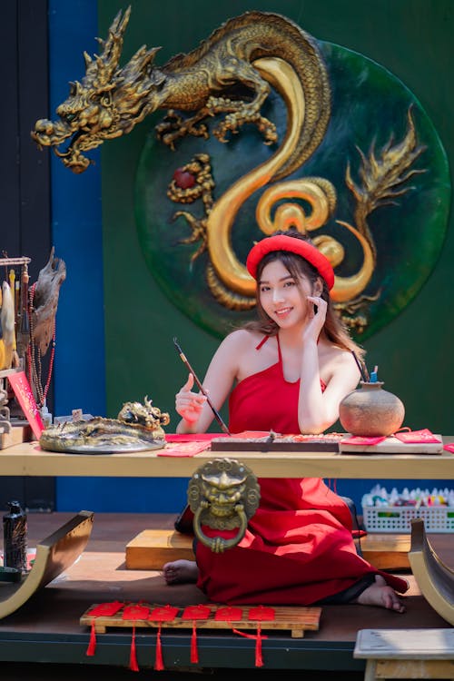 Young Woman in an Ao Dai Dress Sitting at a Table with Traditional Items 