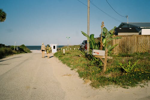 Film Photo of Two People Walking on a Road Toward a Beach 