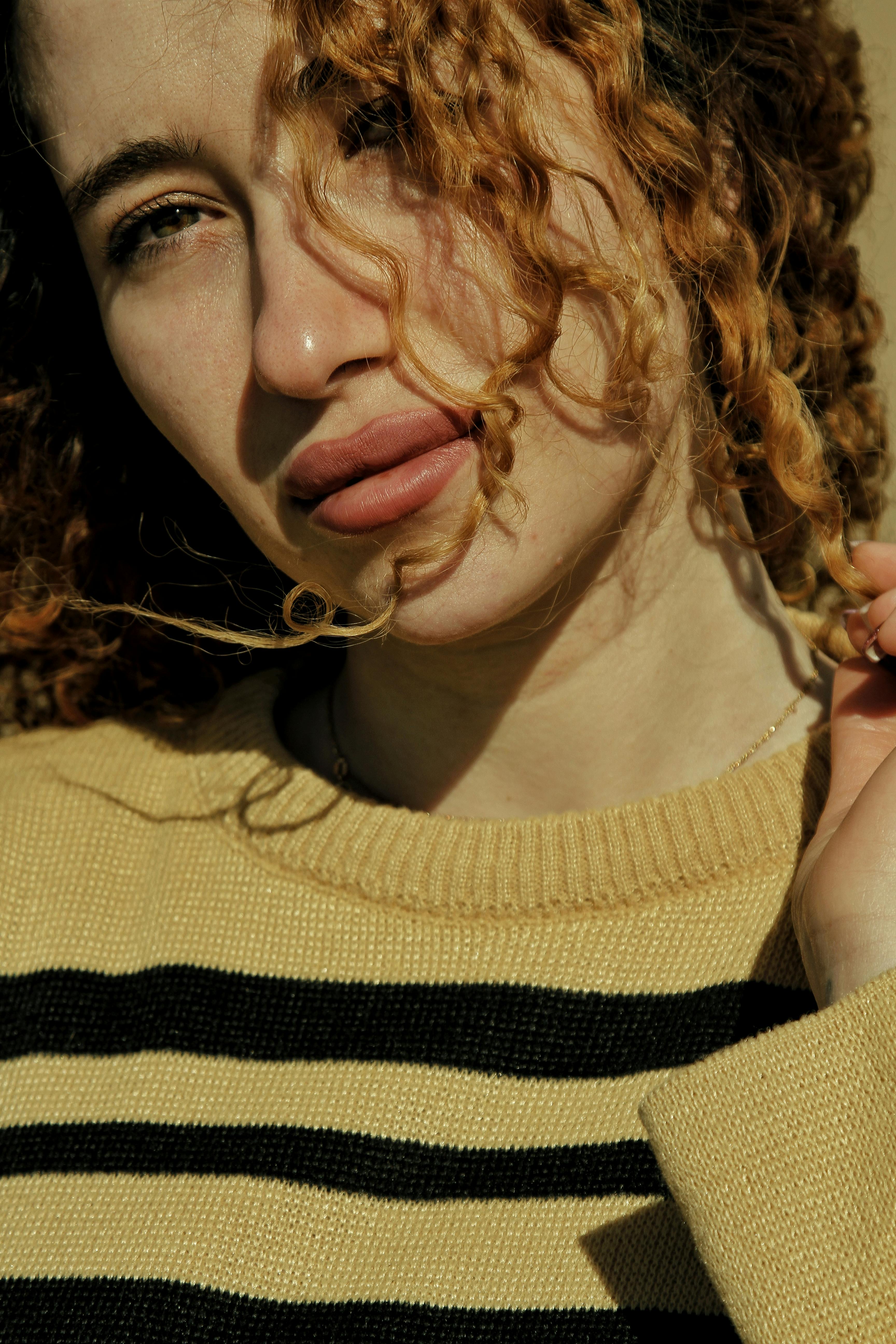 Intimate close-up portrait of a woman with natural curls in sunlight.