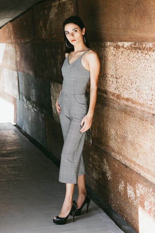 Mujer Con Vestido Gris Sin Mangas De Pie Junto A La Pared Marrón