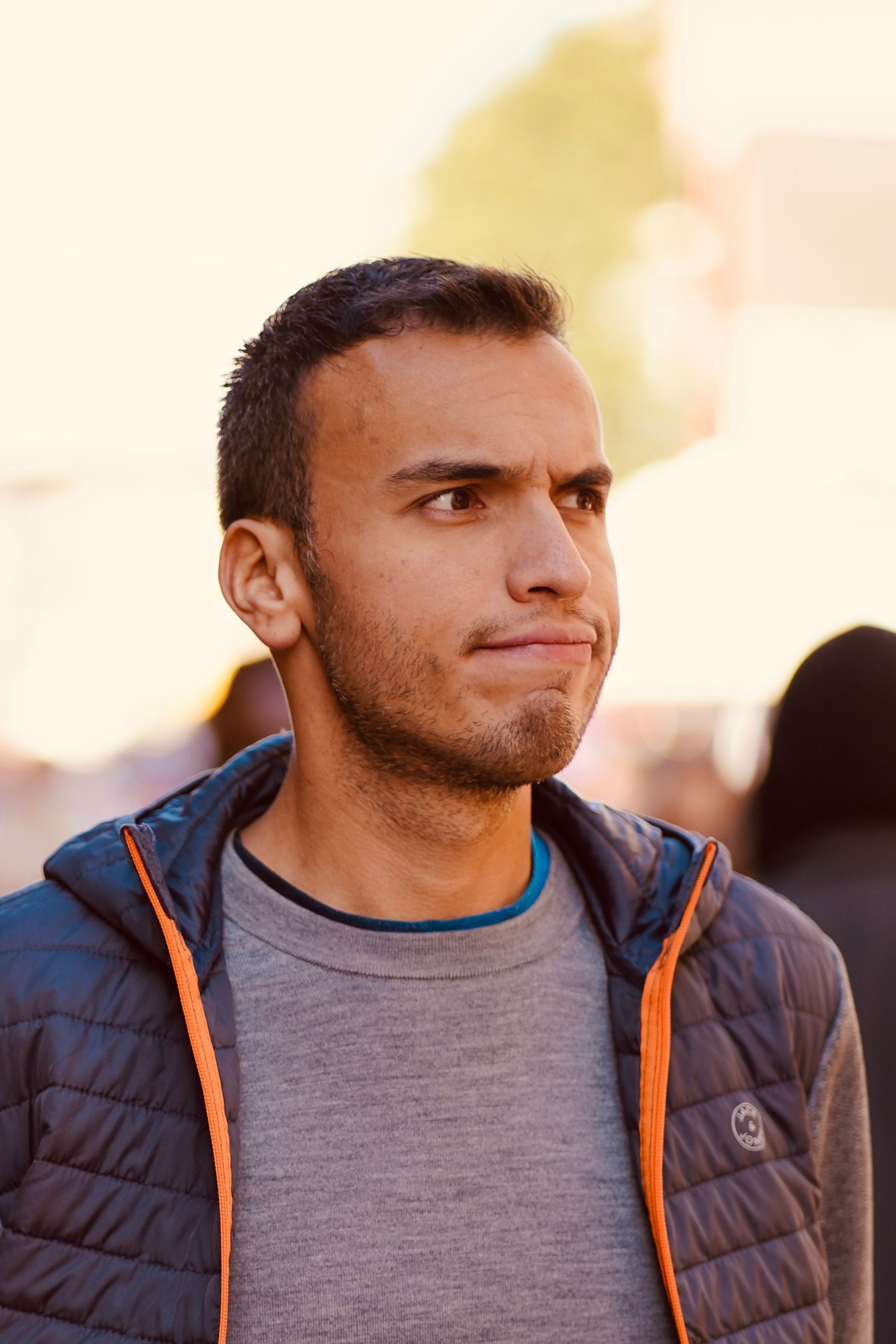Young man in a puffer jacket looking thoughtful outdoors. Casual fashion portrait.