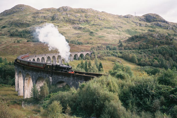 Train Riding On The Glenfinnan Viaduct In The Hills Of Scotland