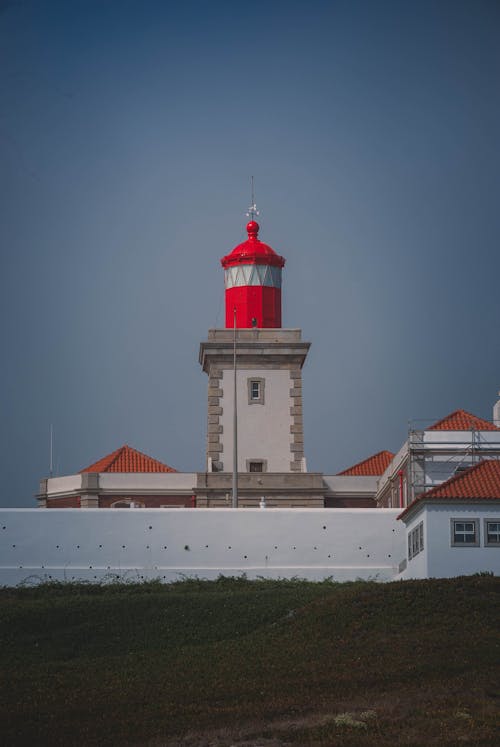 A red and white lighthouse on top of a hill