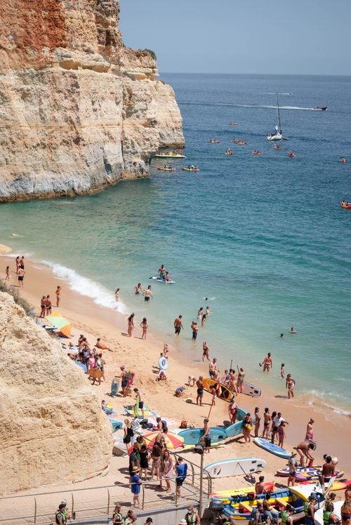 Free Aerial shot of a crowded beach with cliffs, people, and boats on a sunny summer day. Stock Photo