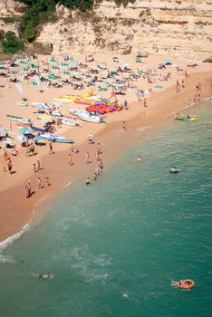 A vibrant summer beach scene captured from above with people sunbathing and swimming.