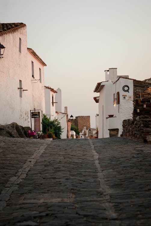 A cobblestone street with white buildings in the background