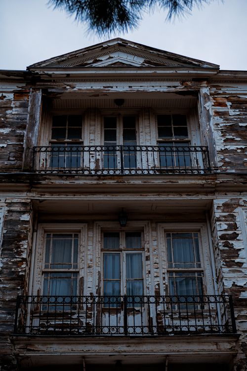 Free Old wooden building with peeling paint and rusty balconies, captured in a dramatic low angle shot. Stock Photo