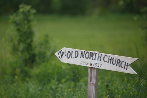 Close-up of a Wooden Arrow Showing the Direction to a Church 