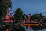 Beautiful night scene of Tivoli Gardens with Pagoda and colorful lights reflected in the lake.