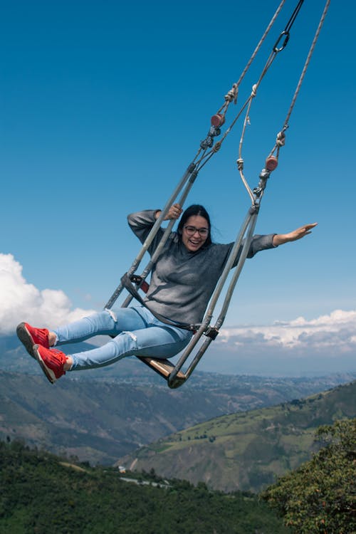Smiling Woman on Swing on Altitude in Mountains