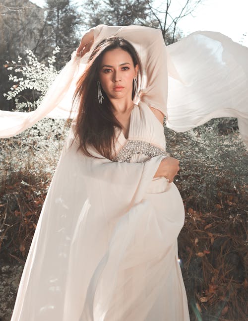 A woman in a white gown is posing for a photo