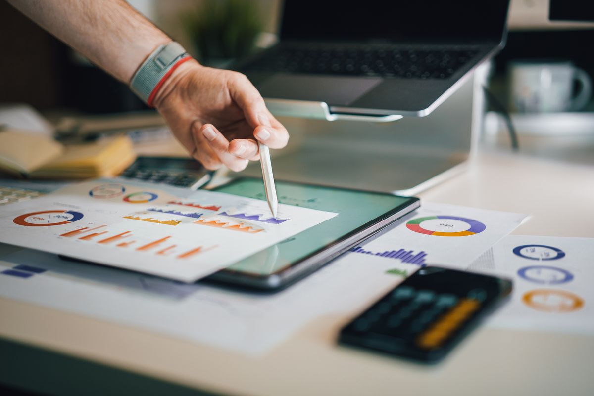 Mãos analisando relatórios financeiros, gráficos e calculadora