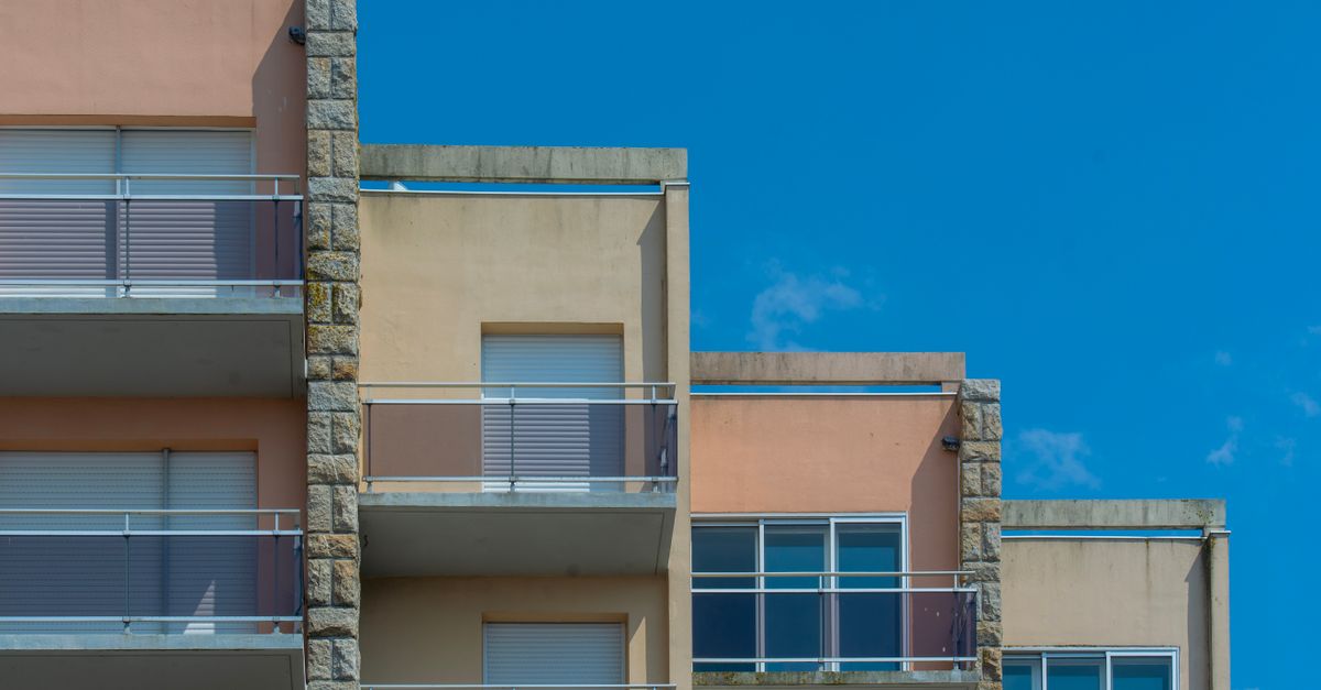 Modern apartment building with balconies against clear blue sky. Urban architecture scene.