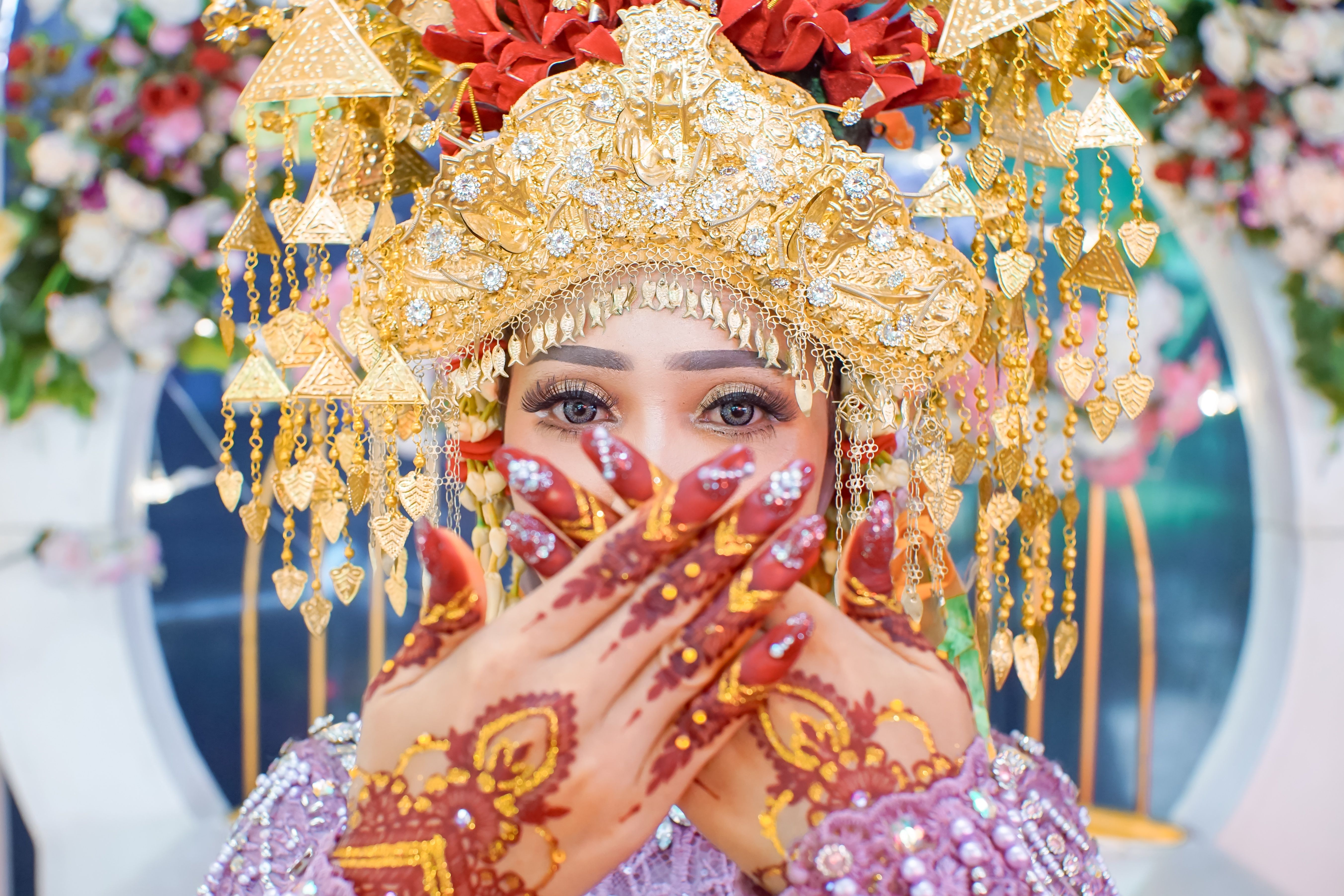 Stunning Asian bride adorned in traditional attire with intricate henna tattoos and gold jewelry.